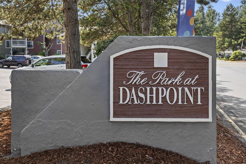A sign that says "The Park at Dashpoint" is in front of a tree.