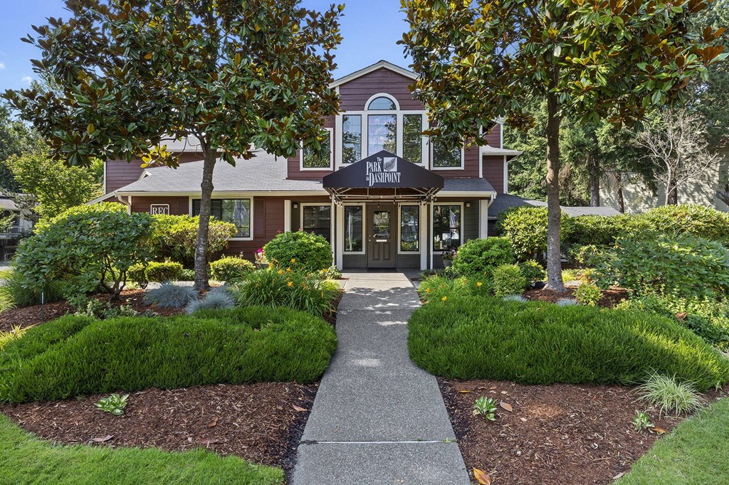A building with a brown roof and a sign that says "PALACE RESTAURANT" is surrounded by trees and bushes.