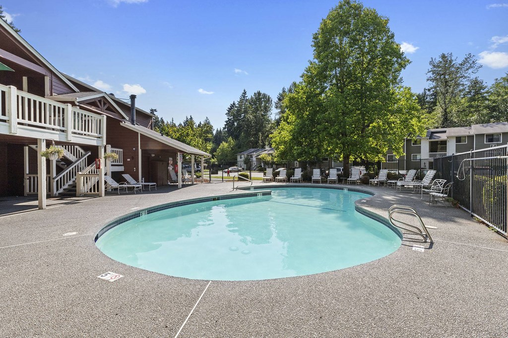 A large outdoor swimming pool surrounded by a fence and trees.