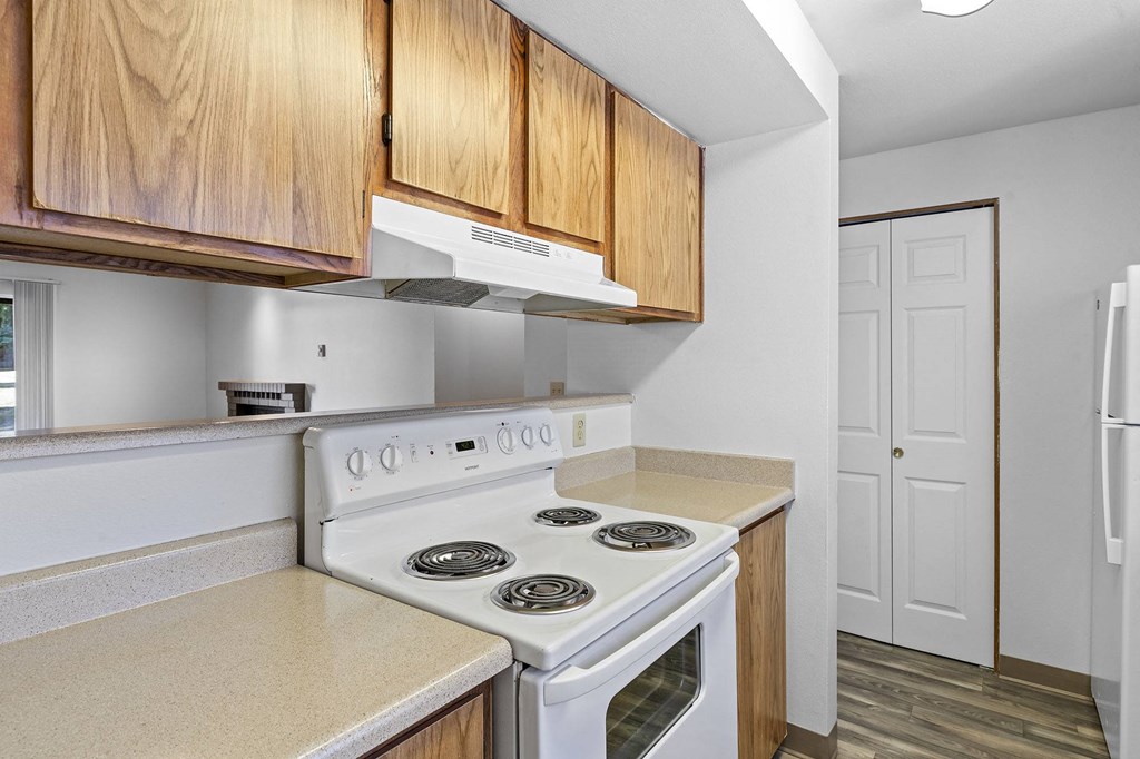 A white stove top oven with four burners and a white range hood above it.
