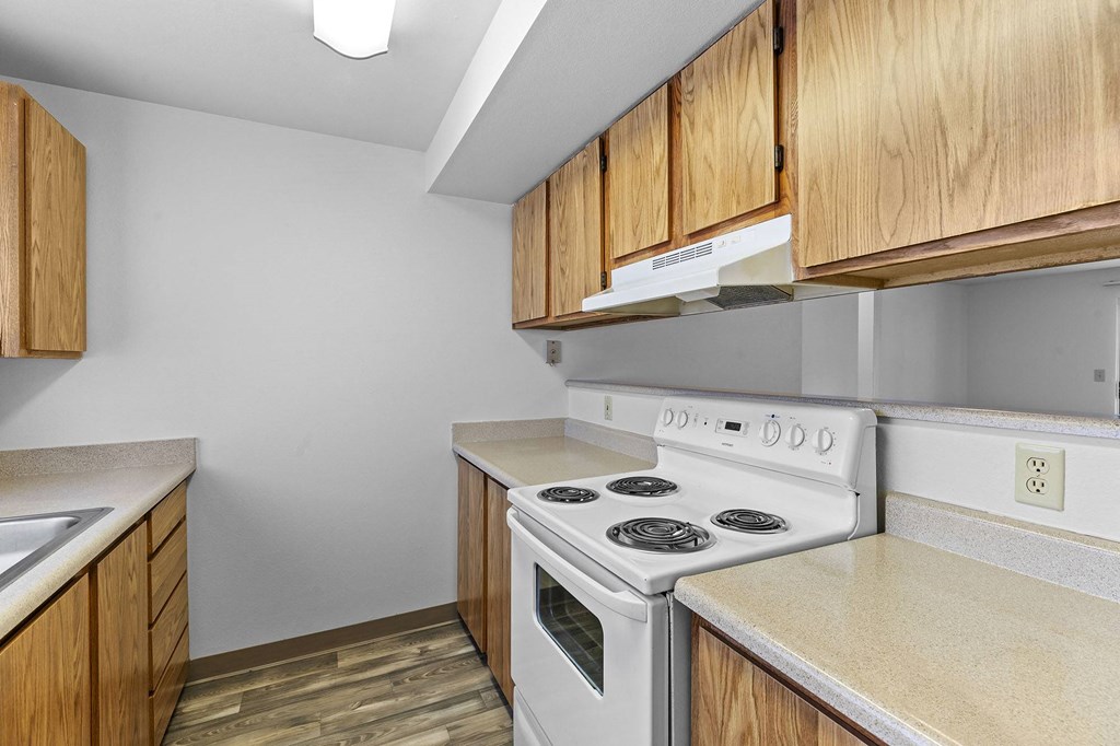 A kitchen with a white stove and wooden cabinets.
