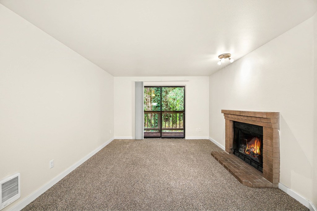 A room with a fireplace and a window with a view of trees.