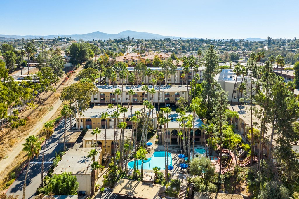 A large building with a pool in the foreground and a mountain in the background.