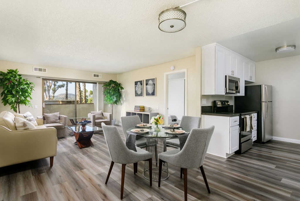 A well-lit, modern kitchen and dining area with a wooden floor and furniture.
