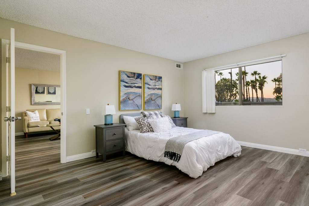 A bedroom with a bed, nightstand, and a painting on the wall.