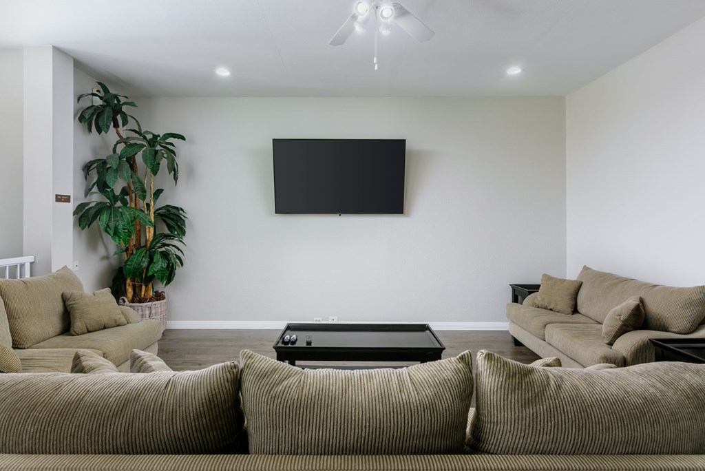 A living room with a large couch and a flat screen TV mounted on the wall.