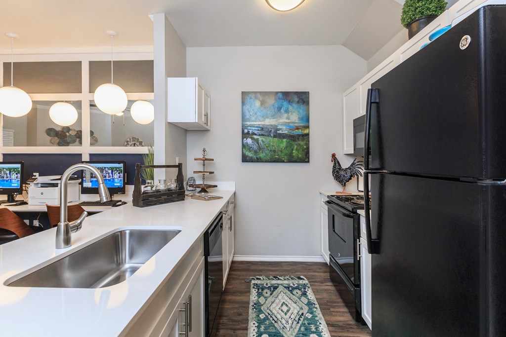 a kitchen with a black refrigerator freezer next to a stove top oven