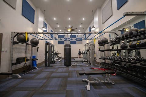 a view of the two story Wynnwood Vinings fitness center with weights and a punching bag in the middle of the room