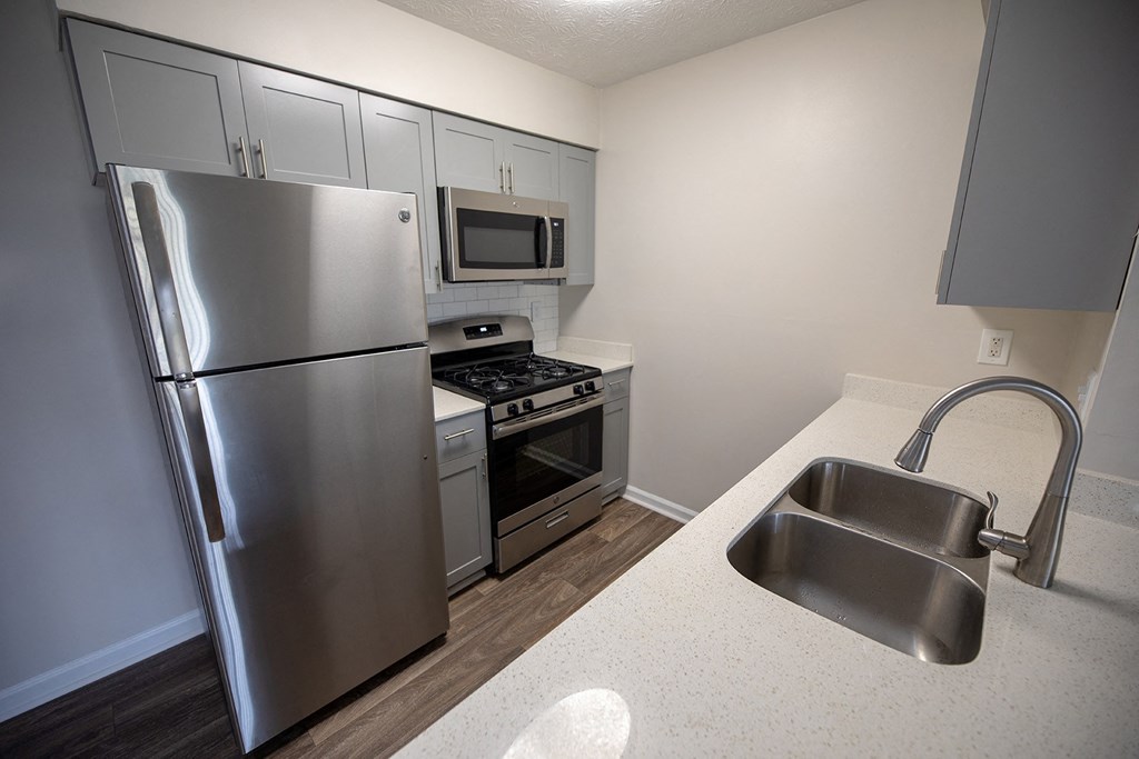 Vinings, GA Apartments for Rent - Wynnwood Vinings - Kitchen with Granite Counters, Stainless Steel Appliances, Grey Cabinetry, White Tile Backsplash, and Hardwood-Style Flooring
