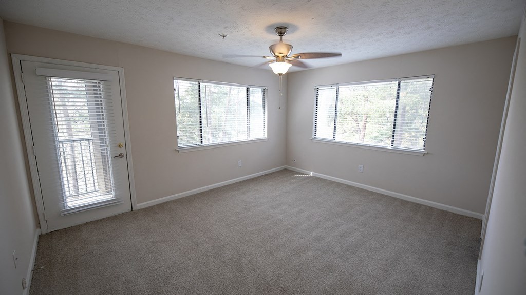an empty bed room with a ceiling fan and three windows with natural sunlight at Wynnwood Vinings Atlanta