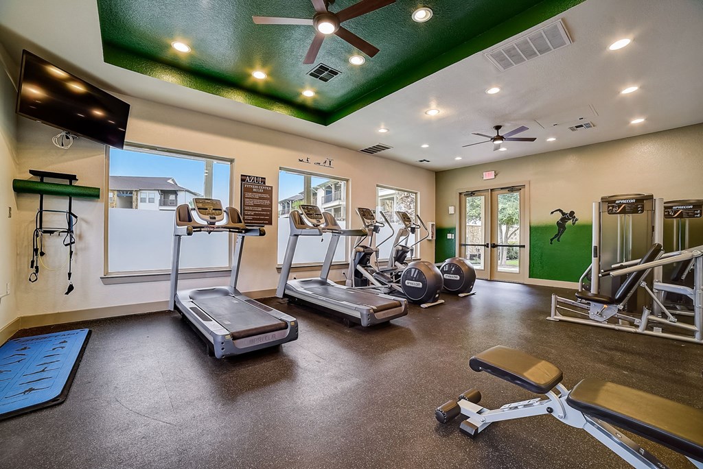 a gym with cardio equipment and a green ceiling