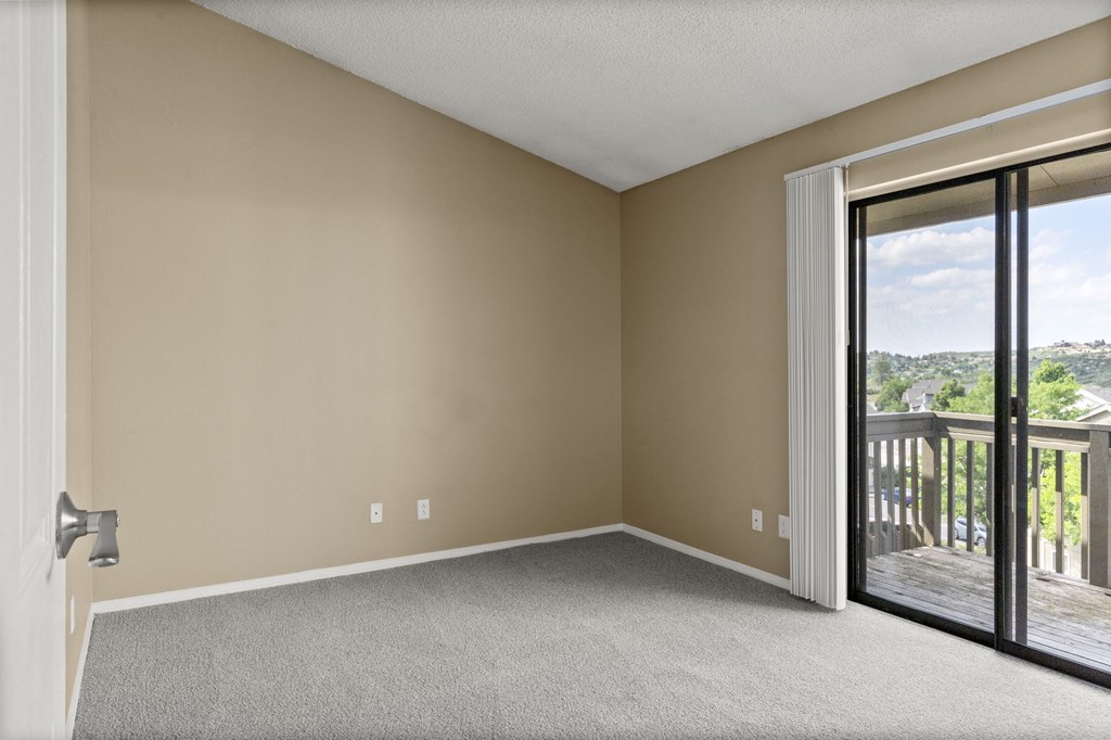 Empty room with a carpeted floor and sliding glass doors.