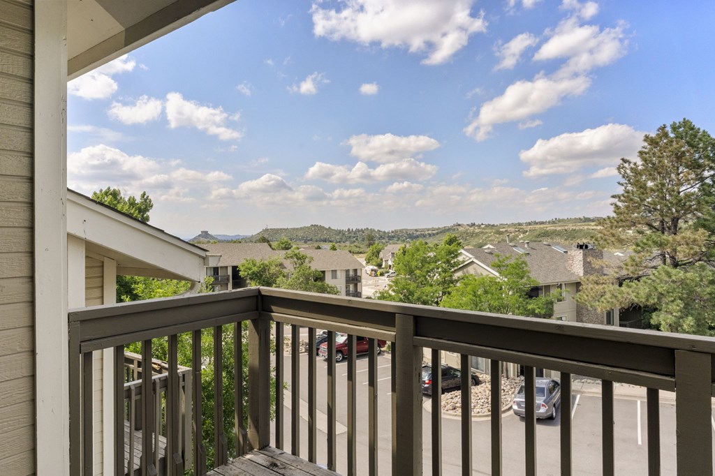 A balcony overlooks a residential area with houses and cars.
