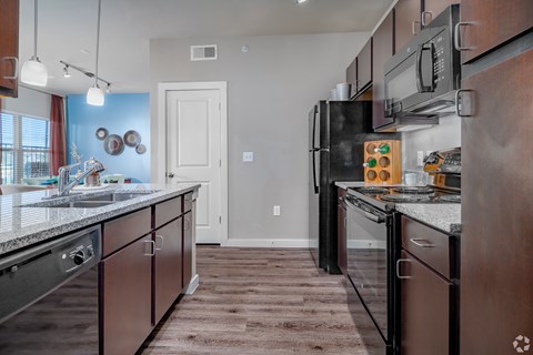 A kitchen with brown cabinets and a black refrigerator.