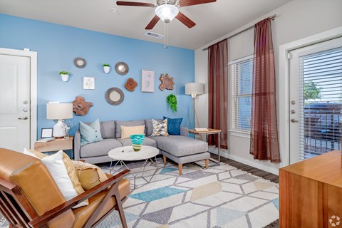 A living room with a blue wall and a ceiling fan.