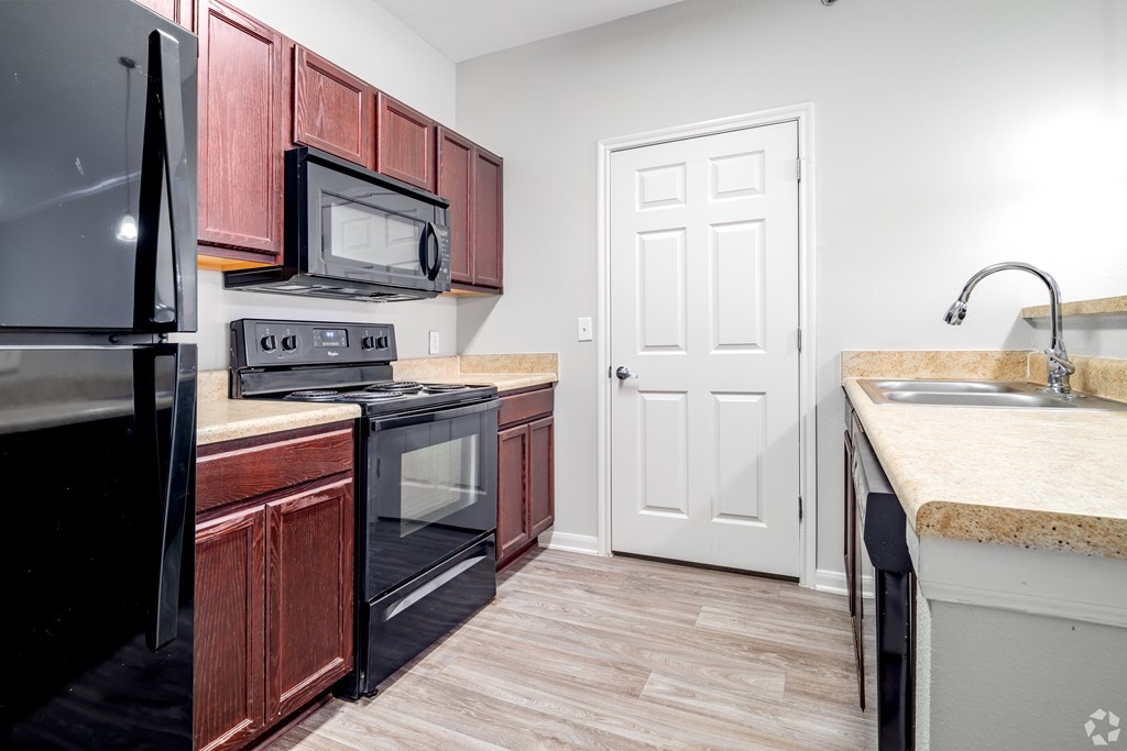 A kitchen with a black refrigerator, black microwave, black oven, and black stove.