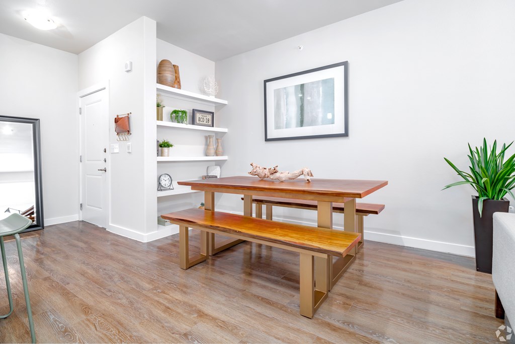 A room with a wooden table and bench, a chair, and a potted plant.