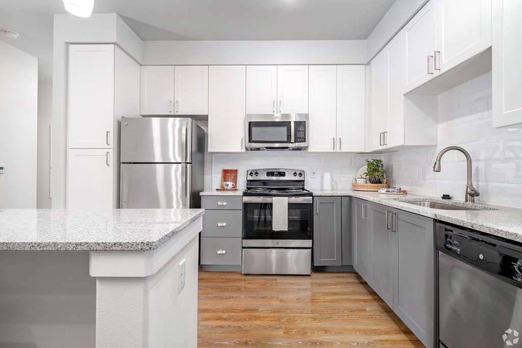 A modern kitchen with stainless steel appliances and wooden floors.