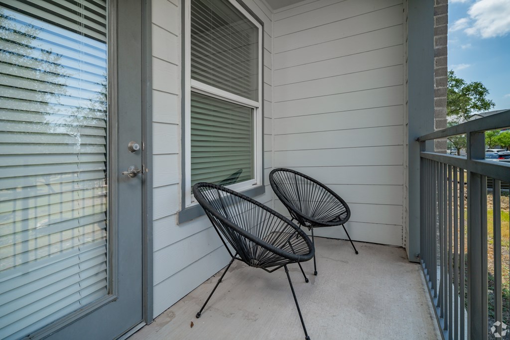 Two black chairs are on a porch.