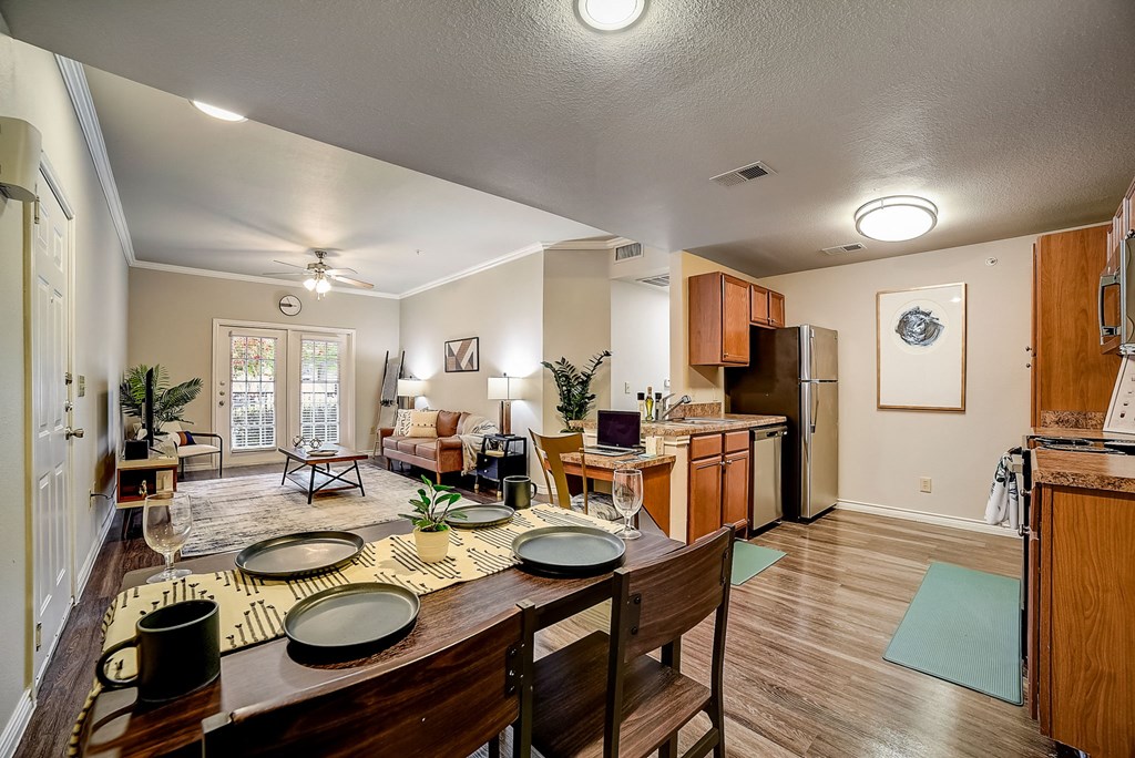 a dining area with a wooden table and chairs and a kitchen in the background