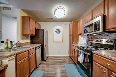 a kitchen with wood cabinets and stainless steel appliances and a stove top oven