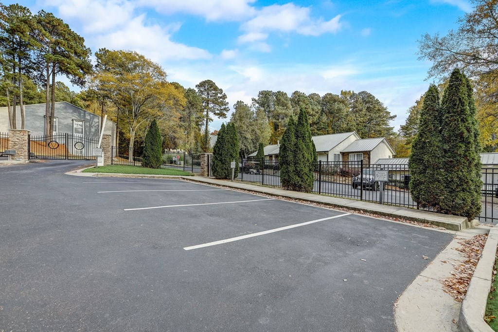 a parking lot with a fence and houses in the background