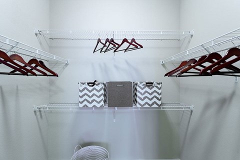 A white closet with clothes hangers and a fan.