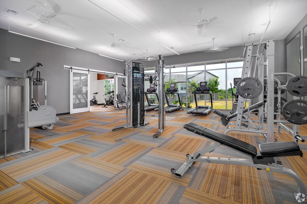 A gym with a variety of equipment including a treadmill, weights, and a bench press.