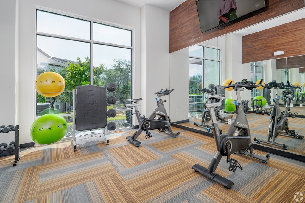 A gym with exercise equipment and a green exercise ball.