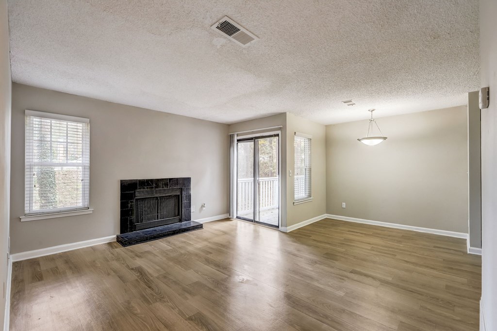 a spacious living room with hardwood floors and black fireplace with glass door to private balcony at Veridian at Sandy Springs apartments
