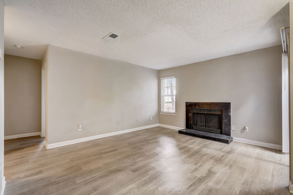 a spacious living room with pet-friendly hardwood floors and black fireplace and natural light at Veridian at Sandy Springs
