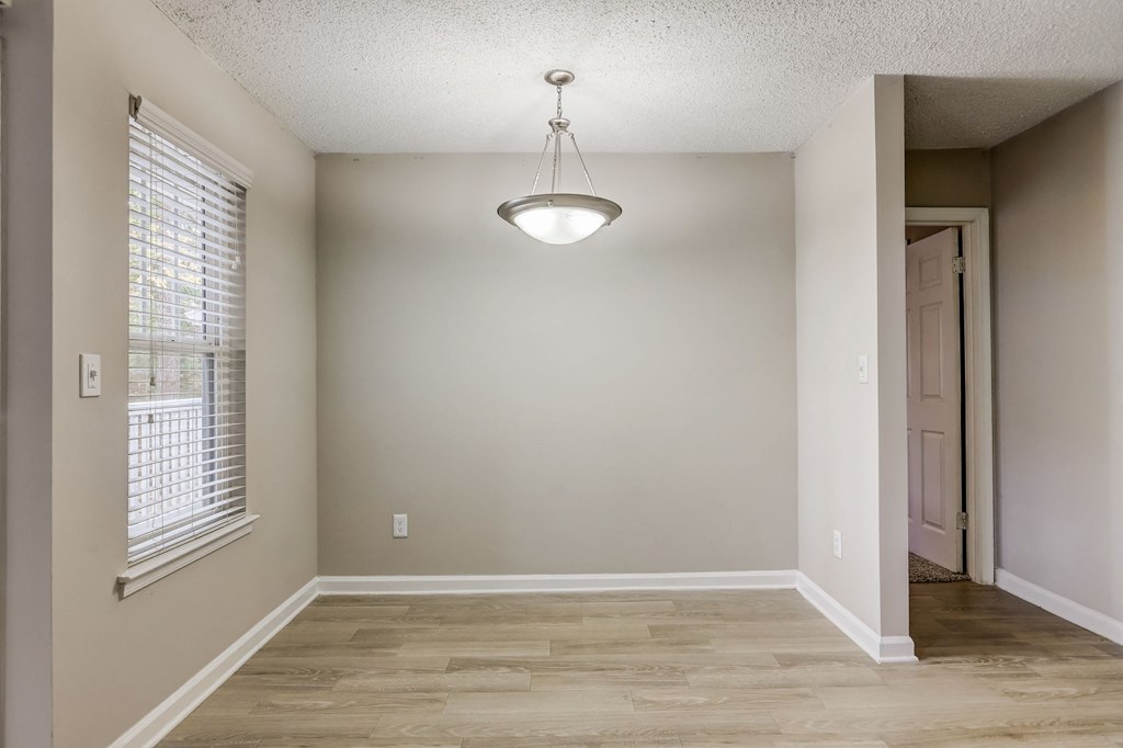 a dining room space with a window and a silver light hanging from the ceiling at Veridian at Sandy Springs