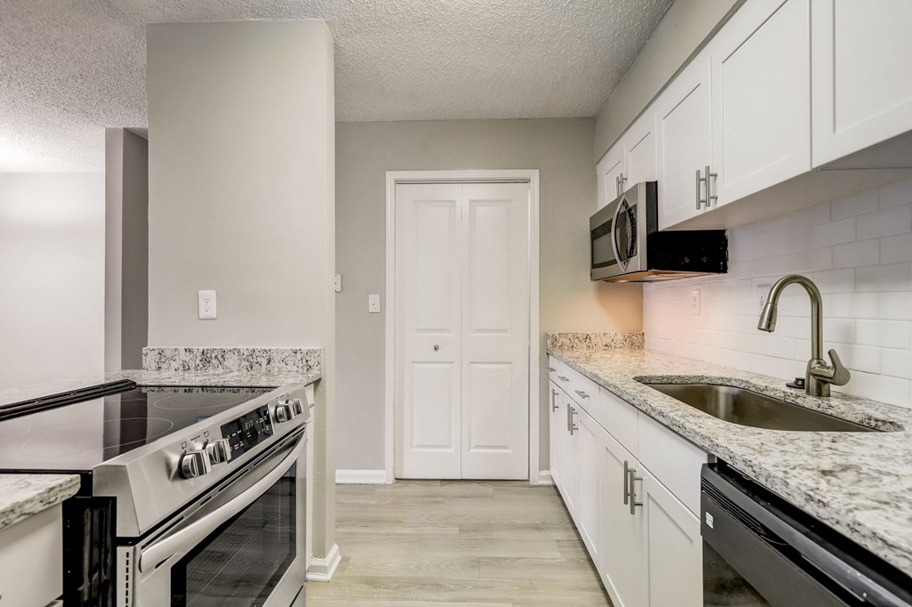 a renovated white kitchen with white cabinets and granite counter tops and a sink at Veridian at Sandy Springs