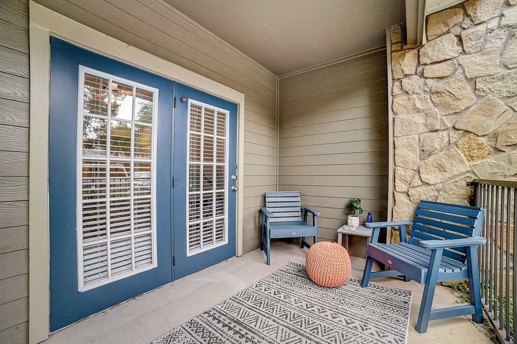 front porch with two chairs and a table with a potted plant