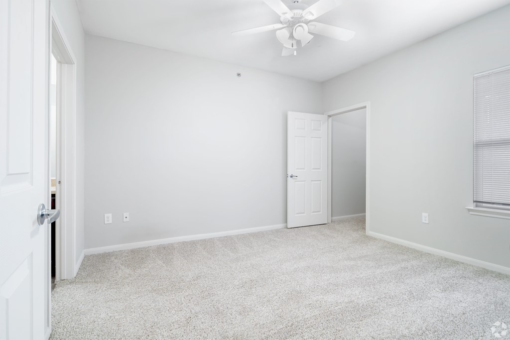 A room with a ceiling fan and carpeted floor.