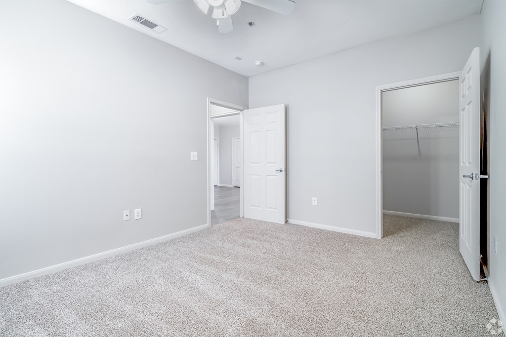 A white room with a carpeted floor and a ceiling fan.