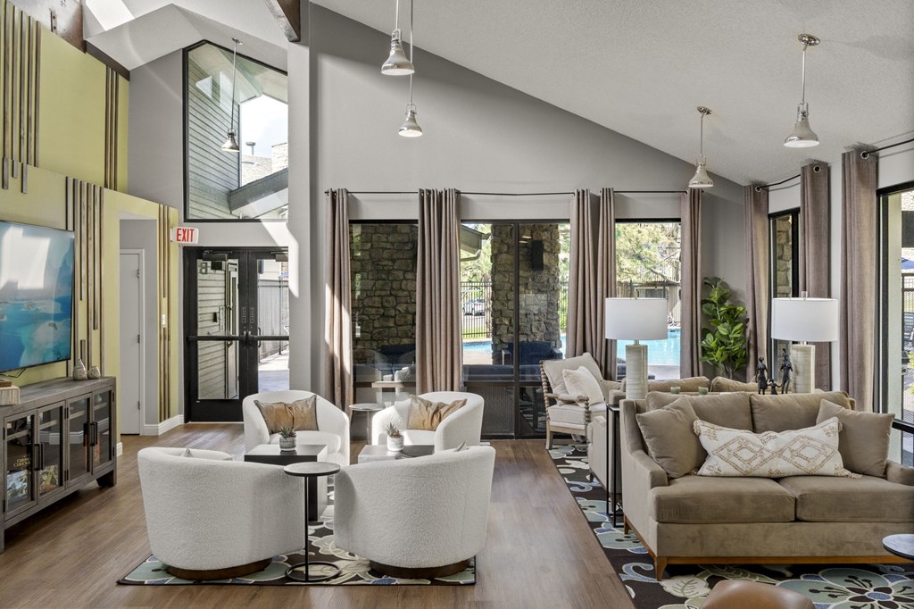 A modern living room with white furniture and a large painting on the wall.