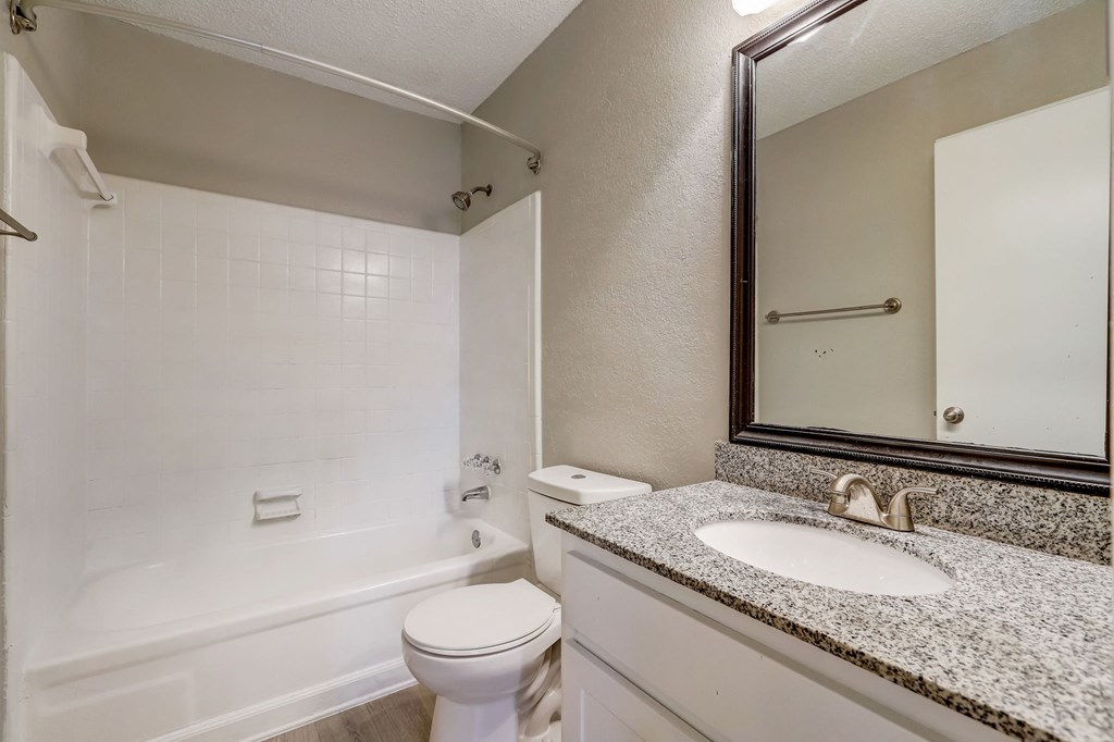 a light colored bathroom with sink and toilet and shower with white tub at Veridian at Sandy Springs