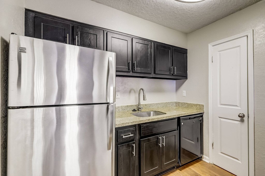a kitchen with black cabinets and a stainless steel refrigerator at Veridian at Sandy Springs