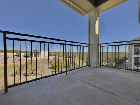 A balcony with a black railing and a concrete floor.