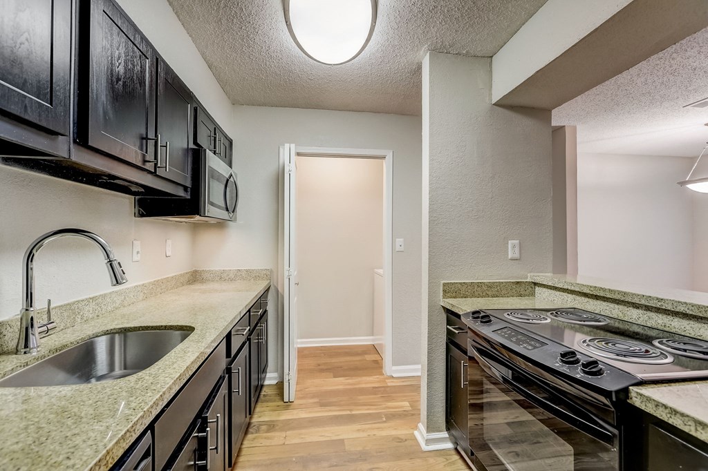 a kitchen with black cabinets and door into a laundry room at Veridian at Sandy Springs