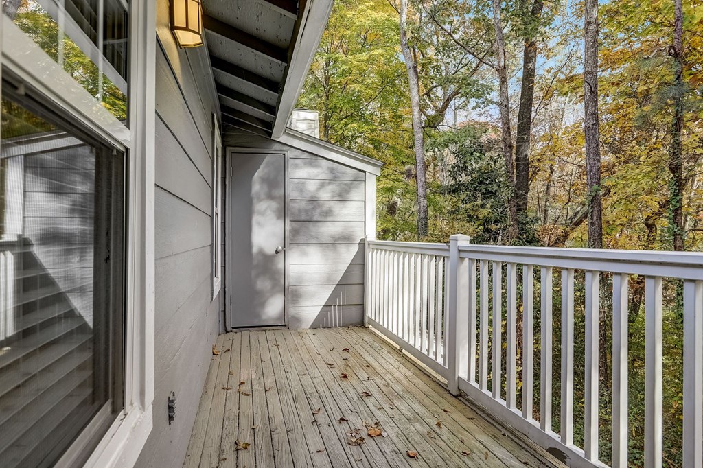 a deck with a view of the woods and a door to a storage closet at Veridian at Sandy Springs