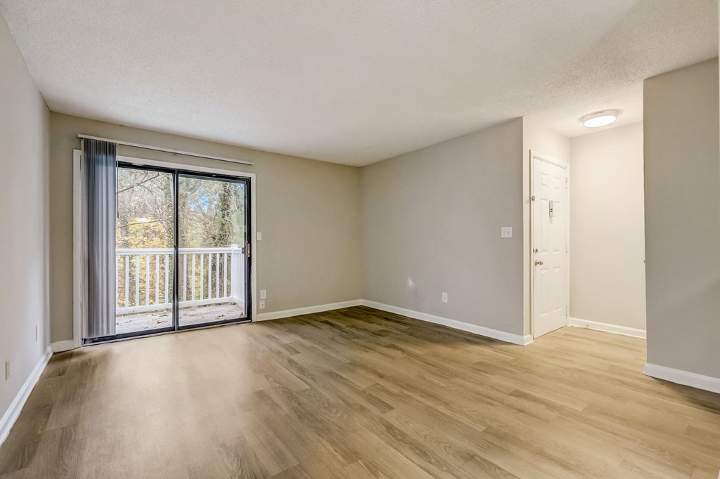 an empty living room with a sliding glass door to a balcony