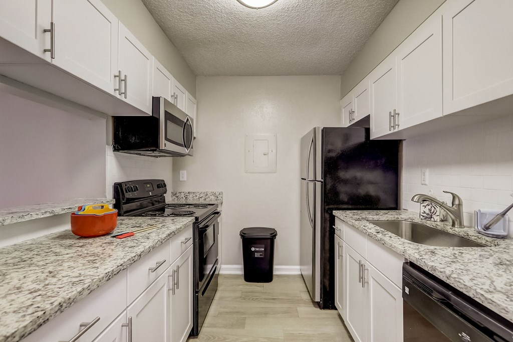 a kitchen with granite counter tops and a stainless steel refrigerator