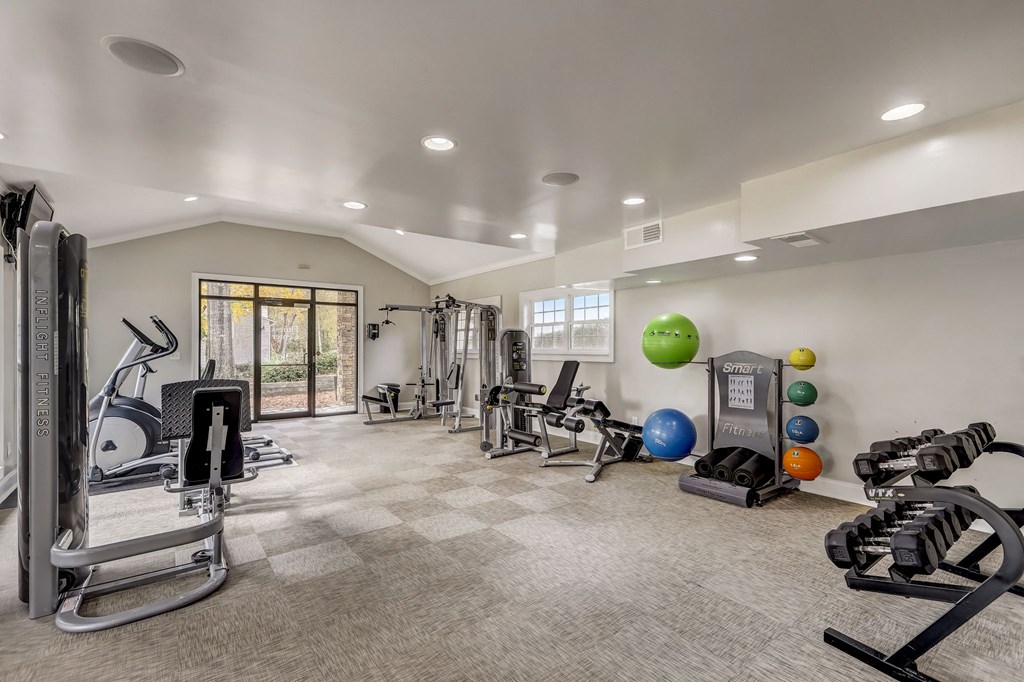 renovated gym with cardio equipment and weights and white walls with natural light