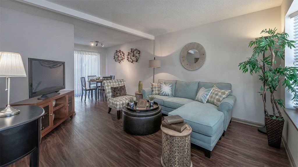 Duluth, GA Apartments with In-Unit Washer and Dryer - Amberlake Village - Furnished Living Room and Dining Ares with Open-Concept Layout, Hardwood-Style Flooring, a Large Window, a Sliding Glass Door to a Private Patio/Balcony, and Modern Light Fixtures