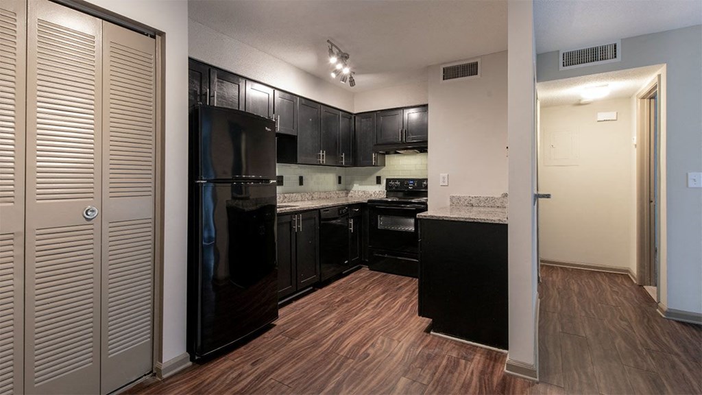 Our kitchen spaces are thoughtfully designed with dark cabinetry, wooden floors, and open spaces