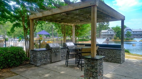 a covered patio with a grill and a table with chairs