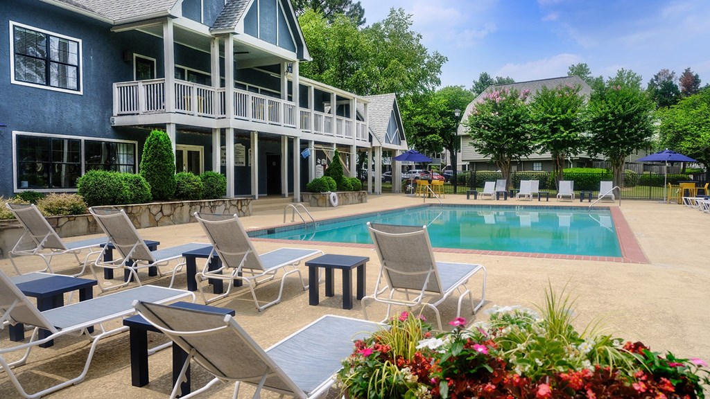 a swimming pool with chaise lounge chairs and a building in the background