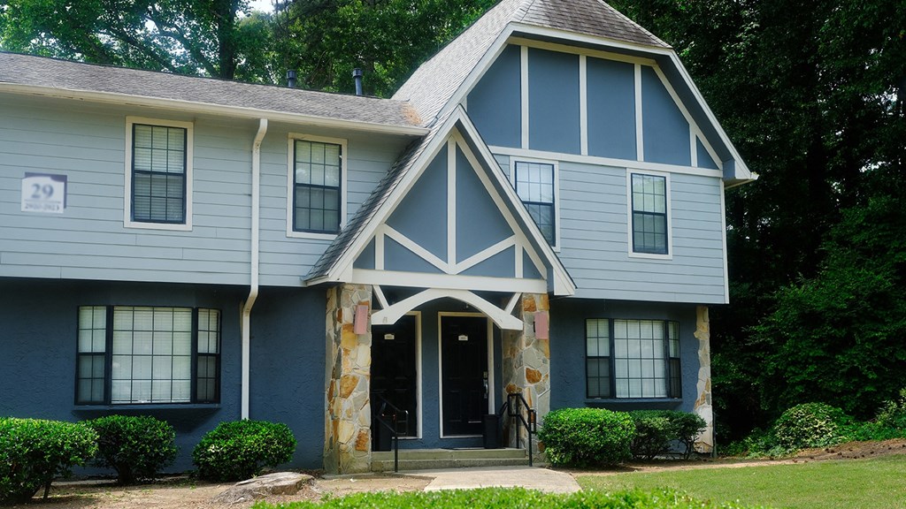Our apartment homes at Amberlake Village with blue siding, white trim, and stone pillars